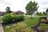Lush landscaped garden with a scenic pathway, vibrant greenery, and cozy gazebo under a cloudy sky, offering serene outdoor living.