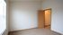 Bright bedroom with plush carpet and a walk-in closet, featuring elegant wood trim and ample natural light from large windows.