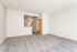 Bright and spacious living area with plush carpet, recessed lighting, and elegant light gray walls, offering a cozy and welcoming atmosphere.