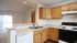 Bright and inviting kitchen with modern appliances, wooden cabinetry, and a breakfast bar leading to a spacious living area with natural light.