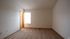 Bright and inviting bedroom with plush carpeting, large window for natural light, and neutral walls for a modern touch.