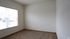 Bright and airy corner of a cozy room with large window, soft carpet, and clean white walls, perfect for a personalized touch.