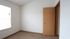 Bright and cozy room with soft carpet and natural light, featuring a wooden door and large window, perfect for a comfortable living space.
