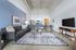 Modern open-plan living space with cozy gray sofa, chic blue accent wall, elegant dining area, and sleek contemporary kitchen.