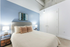 Modern bedroom with soothing blue accent wall, stylish decor, and elegant lighting, creating a relaxing retreat.