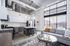 Modern loft-style apartment with high ceilings, large windows, and open-concept living area. Features a sleek kitchen with island seating and stylish pendant lighting.