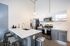Modern apartment kitchen with sleek white countertops, stainless steel appliances, and elegant pendant lighting offering a sophisticated cooking space.