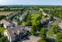 Charming aerial view of a picturesque apartment community surrounded by lush greenery and spacious lawns, offering tranquil suburban living.