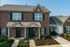 Charming brick townhouse with lush landscaping and inviting entrance, perfect for comfortable suburban living.
