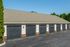 Modern multi-car garage facility with sleek black doors, situated amidst lush green landscaping.