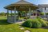 Charming outdoor gazebo nestled in lush greenery, perfect for relaxation and gatherings in a serene neighborhood setting.