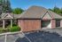 Charming brick building with elegant gable roof and lush landscaping, showcasing roomy garage space and serene surroundings.