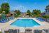 Inviting outdoor swimming pool with elegant lounge chairs under a clear blue sky, surrounded by lush greenery and a charming gazebo.