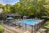 Inviting outdoor pool area surrounded by lush greenery, featuring comfortable lounge chairs and shaded seating for relaxation.