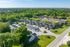 Charming aerial view of a serene apartment complex surrounded by lush greenery, featuring modern townhouses and ample parking.