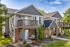 Charming two-story apartment building with inviting private balconies, surrounded by lush greenery and a tranquil setting.