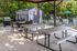 Charming outdoor area with picnic tables and grill, set against a lush greenery background, perfect for gatherings by the poolside.