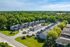 Charming aerial view of a serene residential community surrounded by lush greenery, showcasing modern townhouses and ample parking.