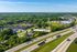 Aerial view of a serene neighborhood with lush greenery, modern homes, and nearby highway access for convenient transportation.