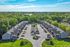 Aerial view of a serene apartment complex with lush greenery and ample parking, perfect for comfortable suburban living.
