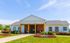 Charming single-story community building with a welcoming porch and vibrant landscaping, set against a bright blue sky.
