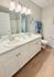 Bright and modern bathroom with dual sinks, elegant quartz countertops, and warm wood flooring.
