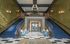 Elegant lobby with dual grand staircases, plush seating, and modern chandelier in a luxurious apartment building.