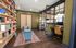 Chic home office with cozy reading nook, elegant bookshelves, rich wood flooring, and modern glass partitions creating a sophisticated ambiance.