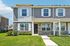 Charming modern townhouse exterior with stone accents, inviting front porch, and lush green lawn under a clear blue sky.