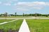 Inviting view from a fresh, green lawn overlooking a wide, open field with vibrant blue skies and fluffy clouds.