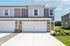 Charming suburban duplex with a modern facade, featuring a spacious two-car garage and well-manicured front lawn.