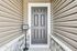 Inviting front entryway featuring a modern gray door with elegant paneling, framed by stylish siding and stone detailing.