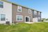 Charming townhouse exterior with modern siding, large sliding glass door, and manicured lawn, perfect for entertaining.