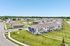 Peaceful suburban neighborhood with charming townhouses, lush green lawns, and a scenic pond featuring a fountain.