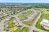 Charming suburban neighborhood aerial view showcasing well-planned streets, modern homes, and lush green spaces with a central pond.