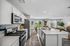 Modern open-concept kitchen and living area with sleek white cabinets, stainless steel appliances, and a bright, airy ambiance overlooking a scenic backyard view.