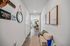 Welcoming apartment hallway featuring stylish decor, mirror, wall art, and cozy seating leading to a bright living room.