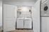 Modern laundry nook with sleek washer and dryer, accented by stylish shelving and artistic decor.