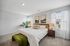Bright and inviting bedroom with elegant decor, featuring a plush king-size bed, stylish bedside tables, artistic wall art, and ample natural light.