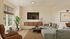 Inviting living room with a chic modern design, featuring a plush sectional sofa, mounted TV, and large window with abundant natural light.