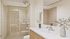 Elegant bathroom with a modern glass shower, sleek vanity, and stylish decor, featuring a warm, inviting atmosphere.