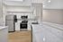 Modern kitchen with sleek stainless steel appliances, elegant white cabinetry, and marbled countertops, perfect for culinary enthusiasts.