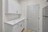 Modern kitchen with sleek marble countertop, elegant white cabinetry, and stainless steel accents.