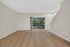 Spacious living area with elegant hardwood floors and large sliding glass doors opening to a lush garden view.