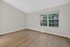 Bright, airy room with sleek wood flooring and a large window offering scenic views of lush greenery.