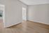 Bright, spacious room with elegant wood flooring and a seamless flow into an adjoining area featuring a stylish white vanity.