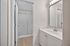 Elegant bathroom featuring a sleek vanity, large mirror, and modern shower with a wood-inspired floor finish.