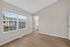 Bright bedroom with large windows, sleek hardwood floors, and a doorway leading to a modern en-suite bathroom.