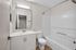 Sleek modern bathroom with elegant white vanity, spacious bathtub, and contemporary fixtures.