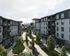 Modern apartment complex with lush greenery, vibrant community areas, and a city skyline backdrop.
